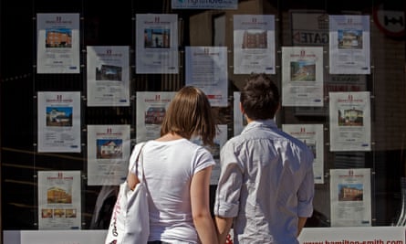 a couple look at homes for sale in an estate agent window