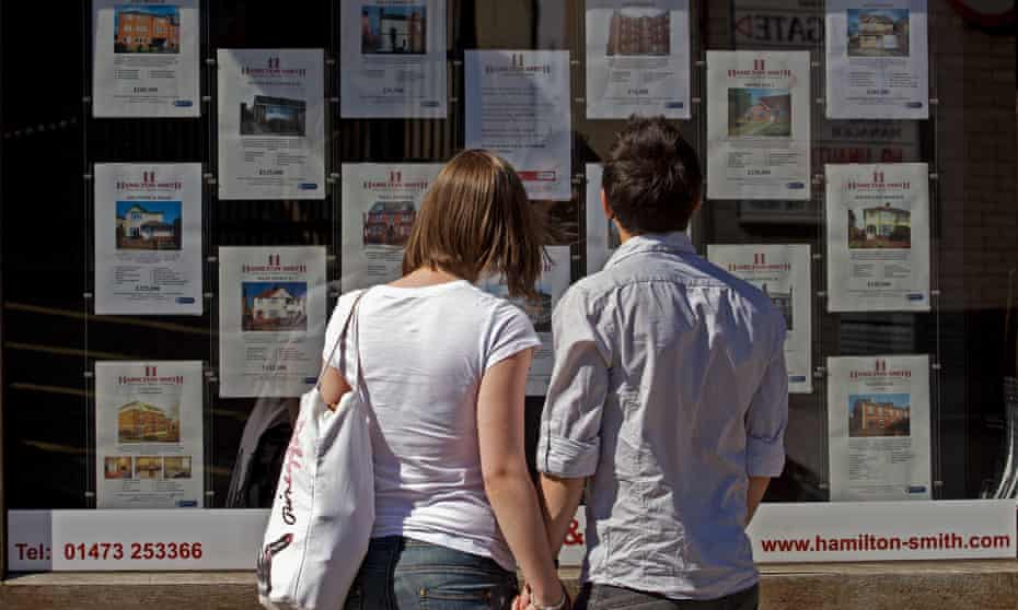 First-time buyers peruse homes for sale in an estate agents window. 