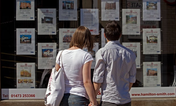 First-time buyers look at houses for sale in a real estate window