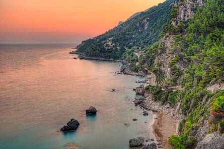 Tiny beach at sunset and wooded cliffs