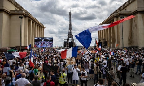 A large group of protesters, some waving French flags, between two buildings with the Eiffel Tower central in the background