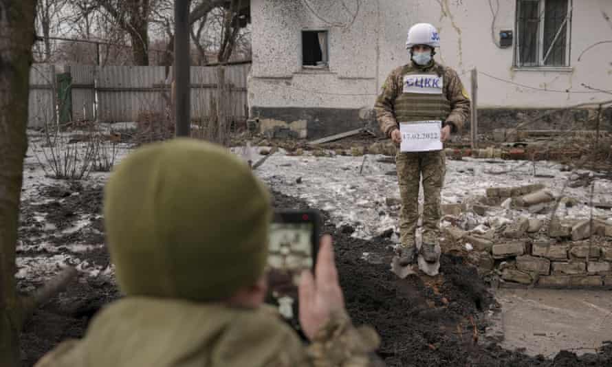 Members of the Joint Centre for Control and Coordination on ceasefire of the demarcation line, or JCCC, take forensic photos of a crater and damage to a house from artillery shell that landed in Vrubivka