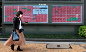 A pedestrian walks past a quotation board displaying share prices of the Tokyo Stock Exchange in Tokyo on 7 April 2020.