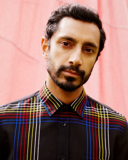 Riz Ahmed wears striped shirt by Saint Laurent.