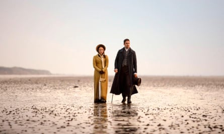 Theo James and Rose Williams wear period costume and walk along a deserted beach