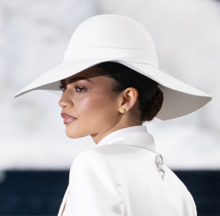 Zendaya wearing a white felt floppy hat and a white jacket with a silver snake brooch on the back