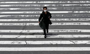 OSAKA, JAPAN - MAY 28: A pedestrian wears a protective mask while crossing the street in the Umeda shopping and entertainment district on May 28, 2021 in Osaka, Japan. The government is expected to announce an extension of the current state of emergency later today as Japan continues to grapple with a fourth wave of coronavirus that has seen hospital beds in Osaka reach 96 percent of capacity and requests for various organizations to cancel the next Olympics. (Photo by Buddhika Weerasinghe / Getty Images)