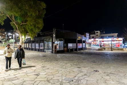 Two people walk past the Square Bar in an otherwise deserted square in Ayia Napa