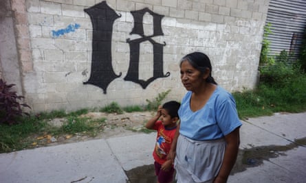 A grandmother and grandson walk by the Barrio18’s insignia in the Ilopango district of San Salvador, El Salvador.