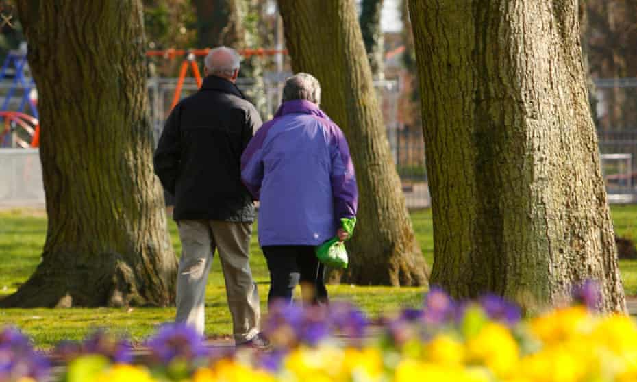 A middle-age couple walking through a park.
