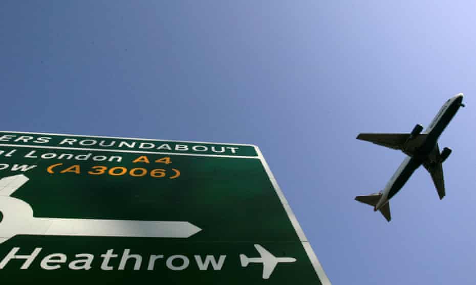 A plane flies over a road sign directing motorists to Heathrow