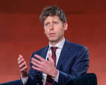 Sam Altman, dressed in a blue suit with a burgundy tie, gestures with his hands while talking on stage