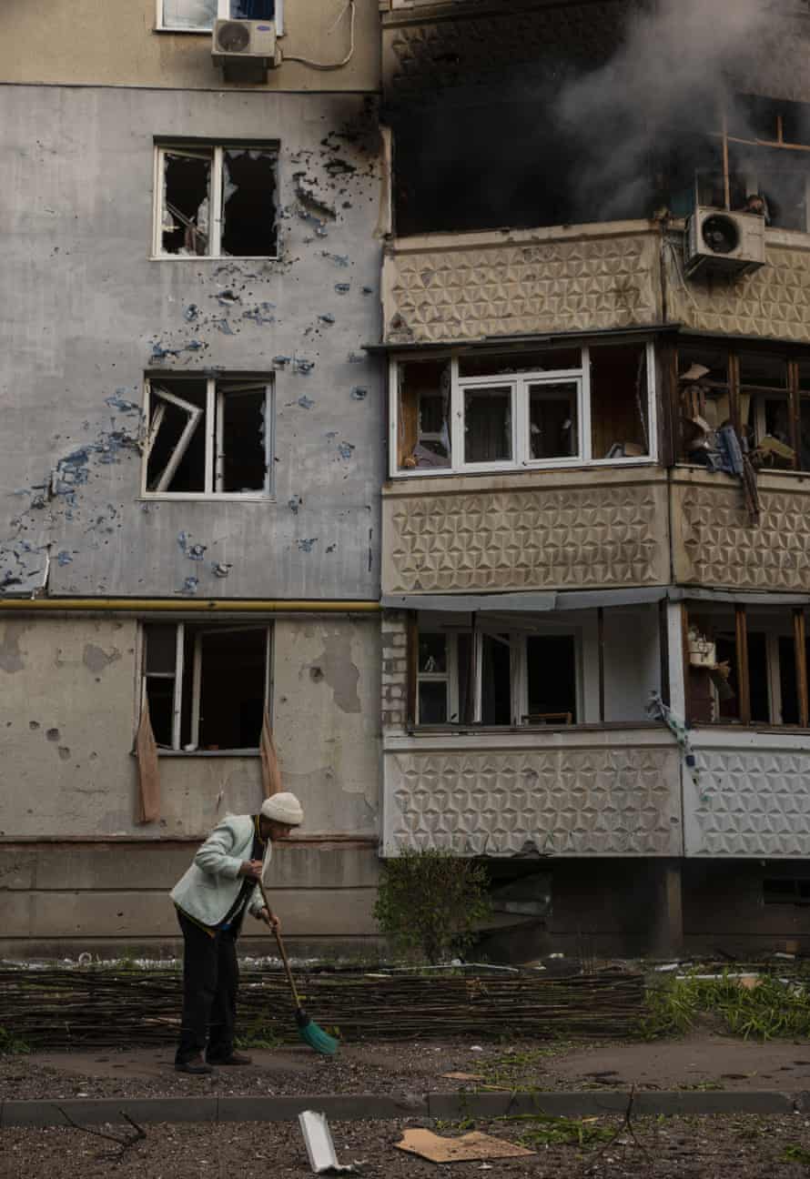 A woman sweeps debris after Russia shelled her building in Saltivka.