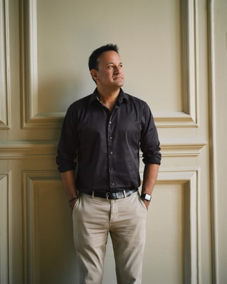 Portrait of Leo Varadkar standing with his hands in his pockets against a panelled wall