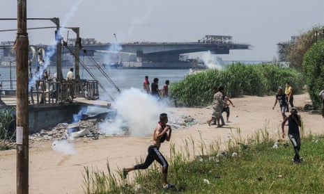 Egyptians run for cover from teargas during clashes with security forces on the Nile island of Warraq