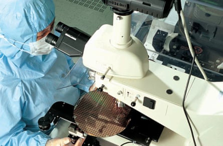 Inside a TSMC fab a scientist looks at through a microscope