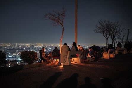 People on a hill at night-time overlooking Tehran