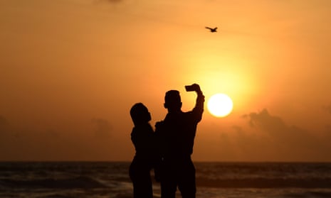 Couple taking a picture on the beach at sunset in Sri Lanka
