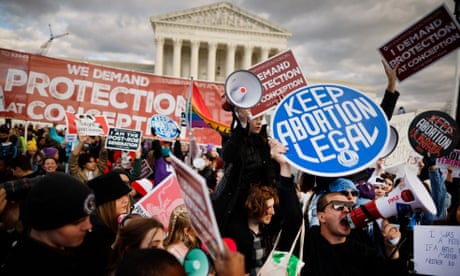 A crowd of people protest in front of the supreme court building.