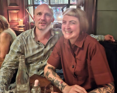A selfie of a man in a check shirt and woman with tattooed arms