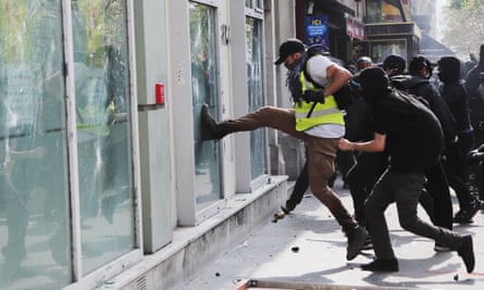 A gilets jaunes protester kicks at the window of a bank in Paris
