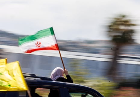 A displaced woman holds an Iranian flag as she makes her way back to her home in southern Lebanon.