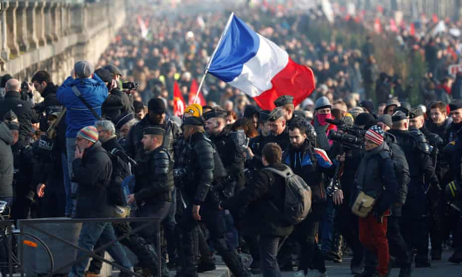 Workers hold a French flag in Paris during a demonstration against pension reforms