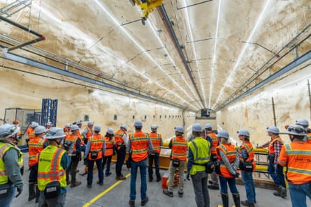 People in hi-vis and hard hats tour a brightly-lit old mine in Lead, South Dakota.