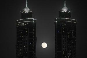 The full moon rises between two towers in Dubai, United Arab Emirates