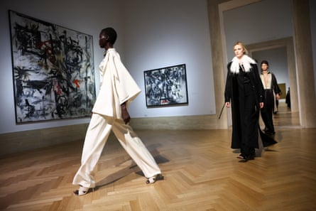 Models walk past painting on gallery wall