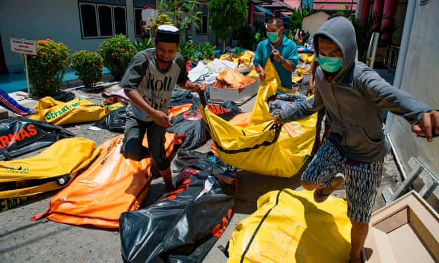 Family members carry the body of a relative to the compounds of a police hospital in Palu