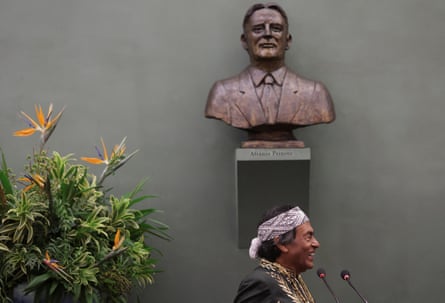 A man wearing a headband in front of microphones under a bust