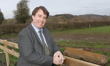 Craig Williams poses for a photo outdoors, leaning on a fence