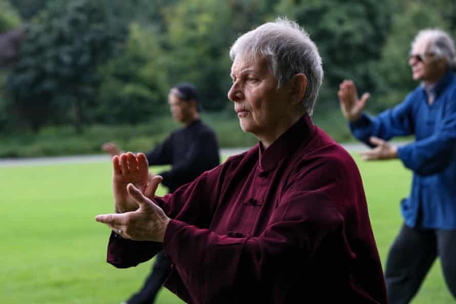 Una mujer como parte de una clase practicando tai chi en un jardín.