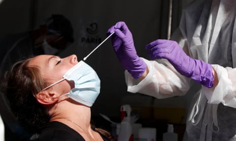 A health worker prepares to administer a nasal swab to a patient at a coronavirus testing site.