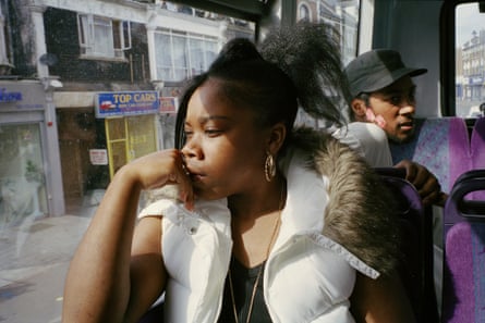 A young woman looks out of the window of a bus, a young man sitting behind her looking the other way