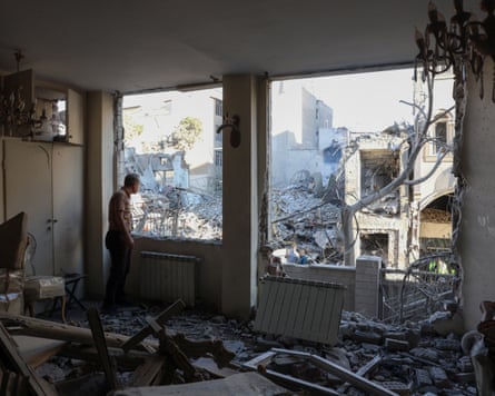 An Iranian resident looks out of the window of his damaged home after Israeli-American strikes during the current conflict