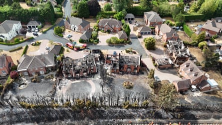An aerial view of burnt-out houses with charred trees and land in the foreground