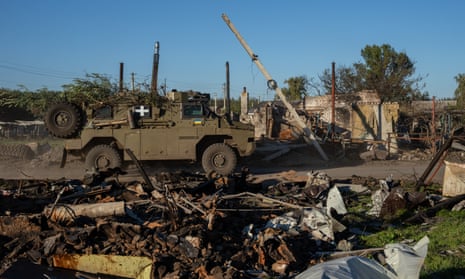 An Australian-built Bushmaster armoured vehicle is driven past destroyed buildings on 8 October 2022 in Lozove, Ukraine.