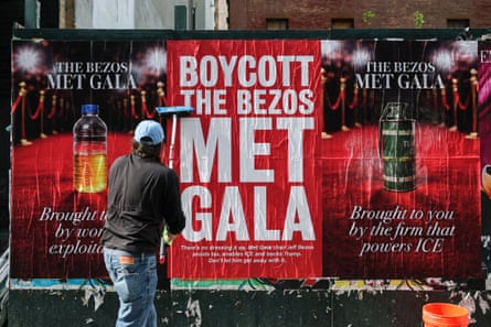 A person puts up a poster that says ‘boycott the Bezos Met Gala’