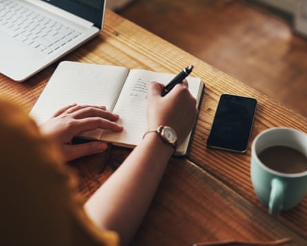 Shot of an unrecognisable woman writing in a notebook while working from home
