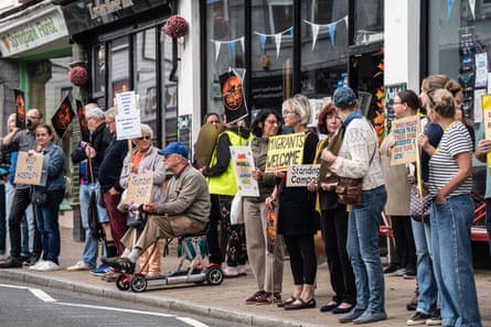 A line of people holding signs that say ‘we all rely on strangers’ and ‘keep racism off our streets’