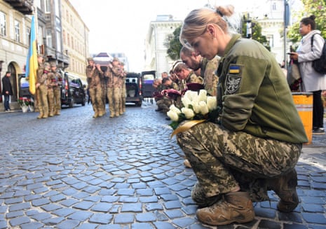 Ukrainian soldiers take a knee as their comrades carry coffins during a funeral ceremony in Lviv.