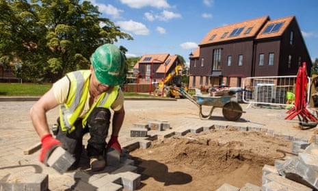 Worker lays paving in front of new houses