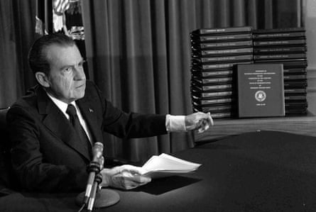 A black and white image of a man pointing to a stack of documents