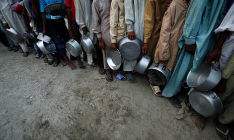 Flood victims holding their plates stand in queue for food handouts in Pakistan.