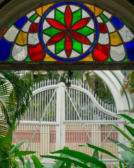 A arched window of stained glass looking out to an entrance gate