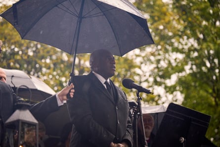 David Lammy speaks into a microphone as an umbrella is held over his head.