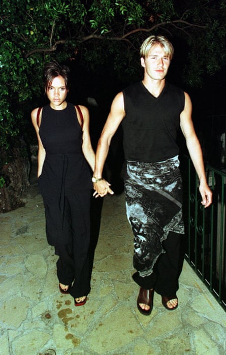 David Beckham on a night out, wearing a sarong holds the hand of Victoria Adams hand