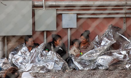 Migrants wait under blankets.